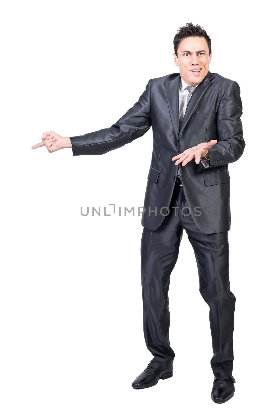 Full body of astonished man pointing aside and looking at camera with confused face isolated on white background in studio