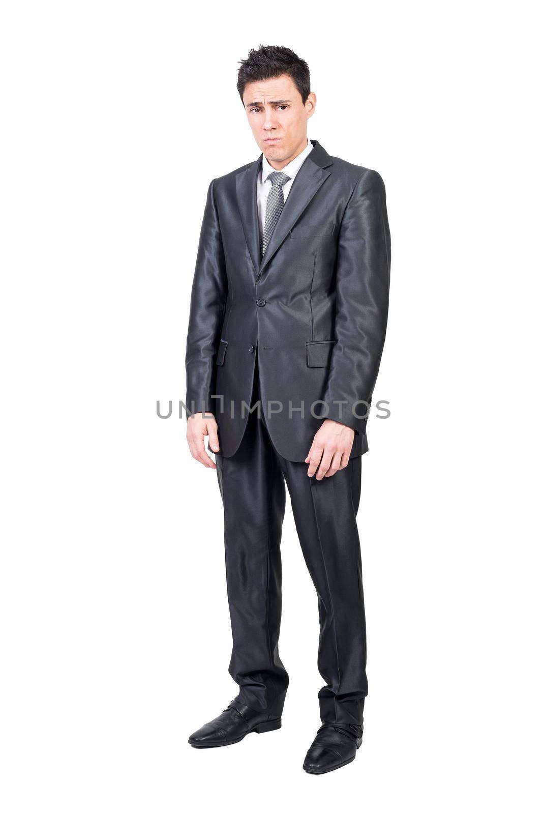 Full body of sad young male manager with short dark hair in elegant suit and tie standing against white background and looking at camera with frustration