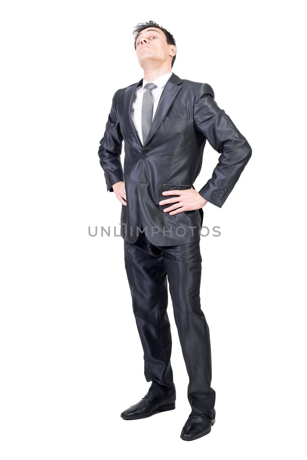 Full body of self assured young male executive manager in elegant suit and tie standing against white background with hands on waist and looking at camera with arrogance