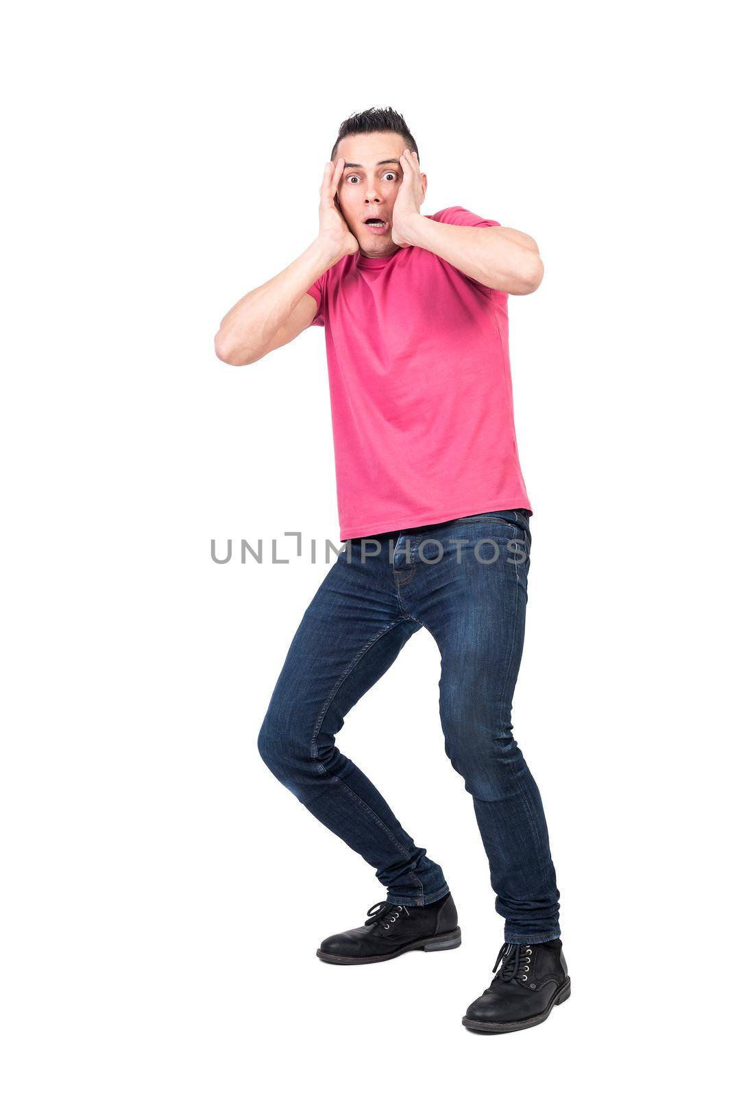 Full length frightened male in casual clothes looking at camera and touching head in distress while staggering back from danger against white background