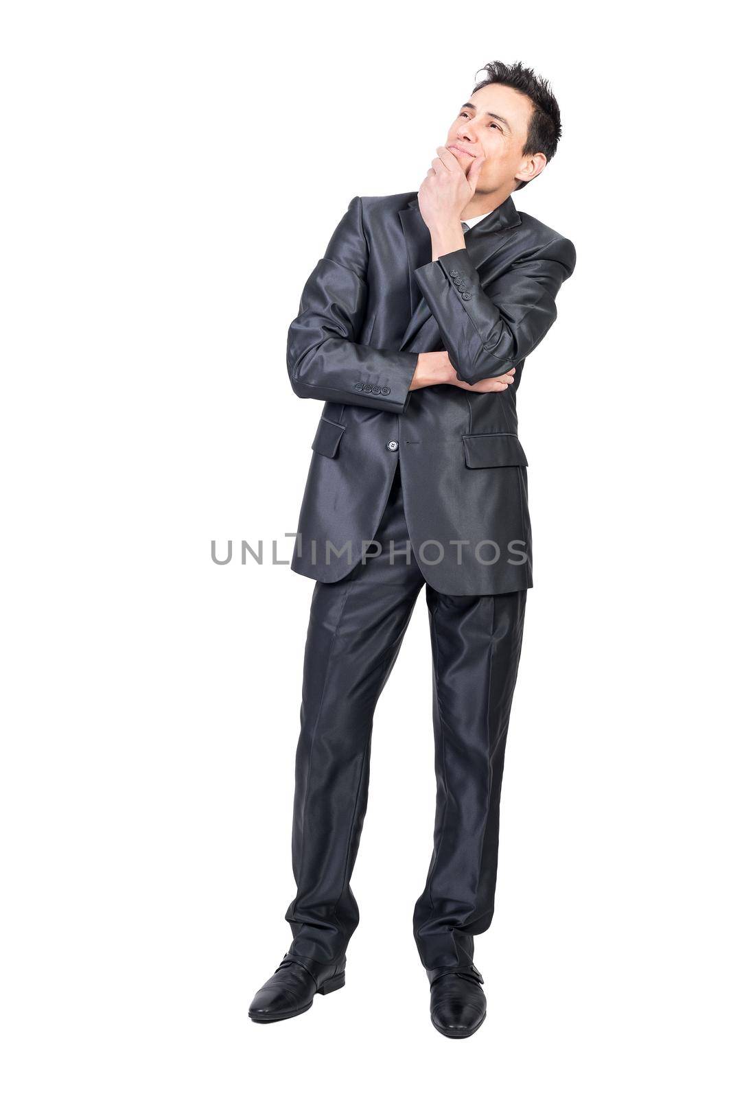 Full body of elegant young male manager with dark hair in classy suit touching chin and looking away dreamily in white studio