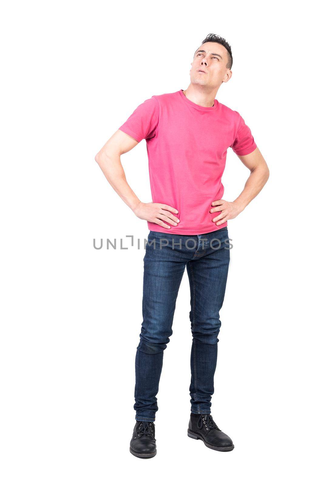 Full body suspicious male holding hands on waist and looking up while pondering over problem against white background