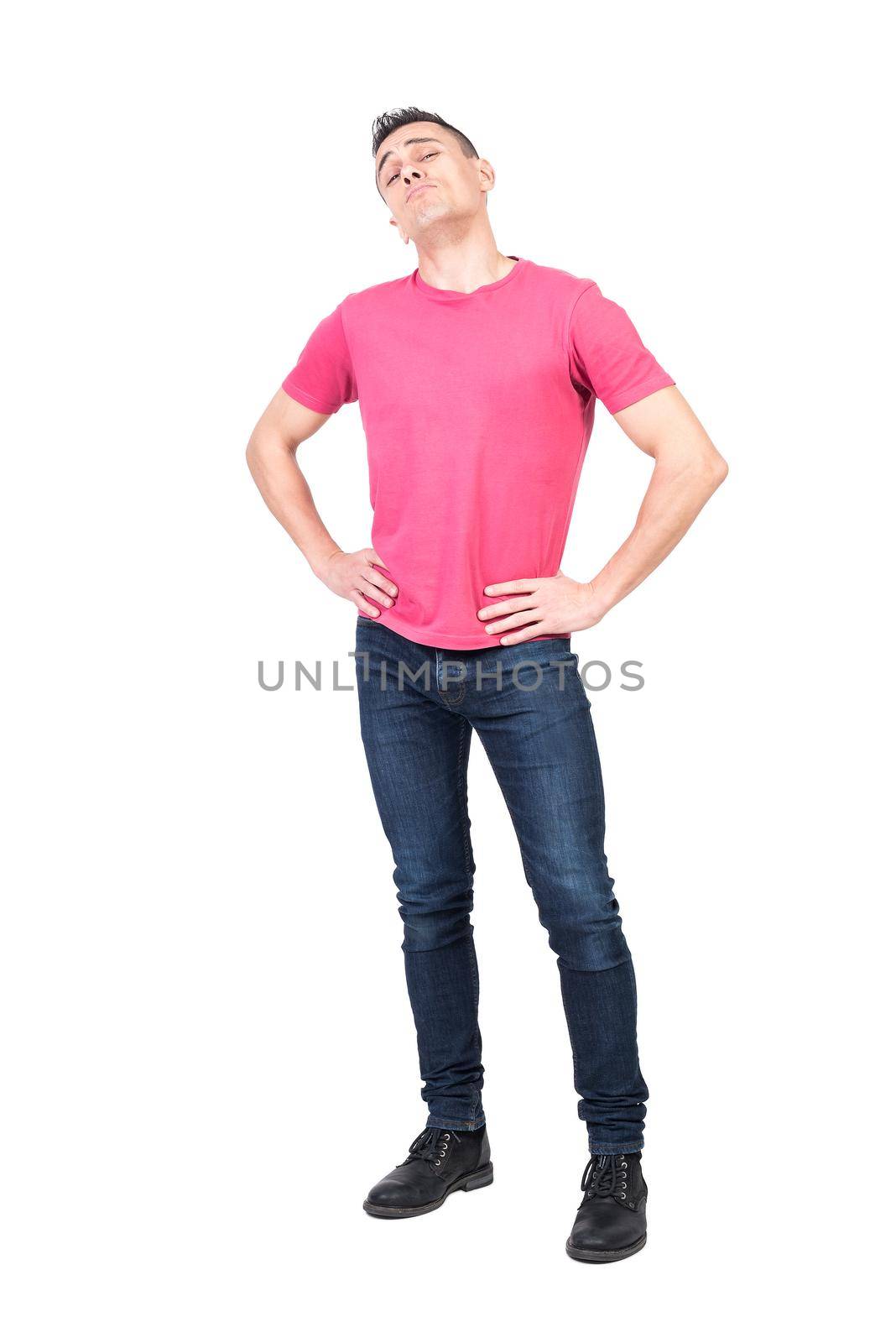 Confident man in jeans and pink t shirt holding hands on waist and looking at camera with proud face expression isolated on white background