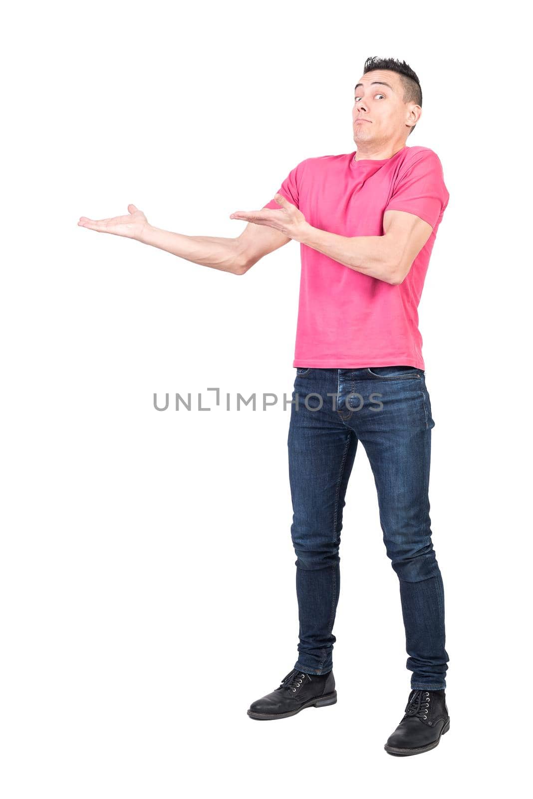 Full body of confused male model in casual outfit pointing aside and looking at camera with amazed face isolated on white background