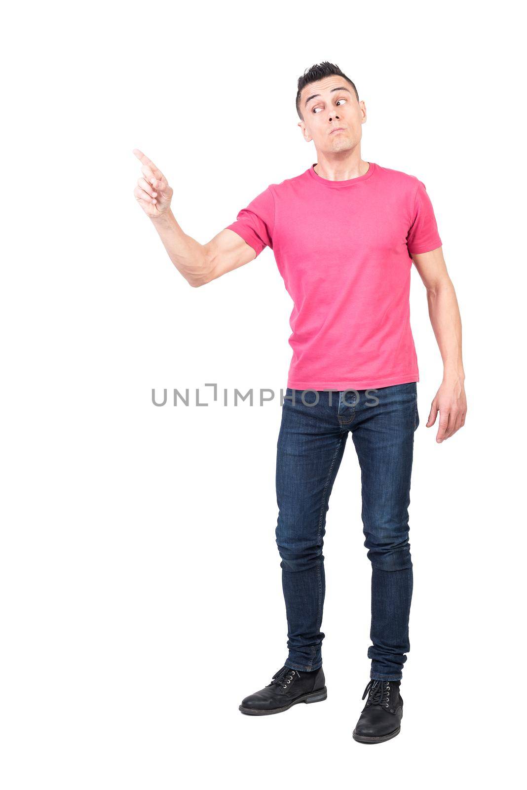 Full length man in jeans and pink t shirt pointing away with index finger while confronting opponent isolated on white background