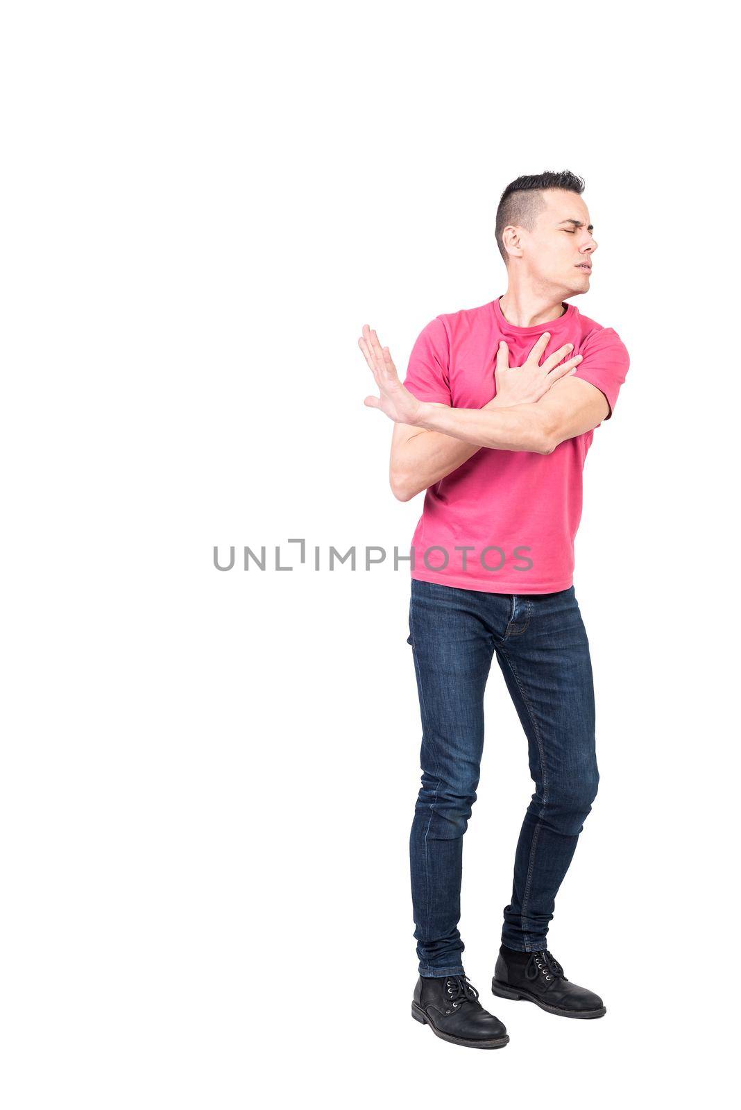 Full length of young serious guy with dark hair in casual clothes touching hearts and showing stop gesture with closed eyes isolated on white background