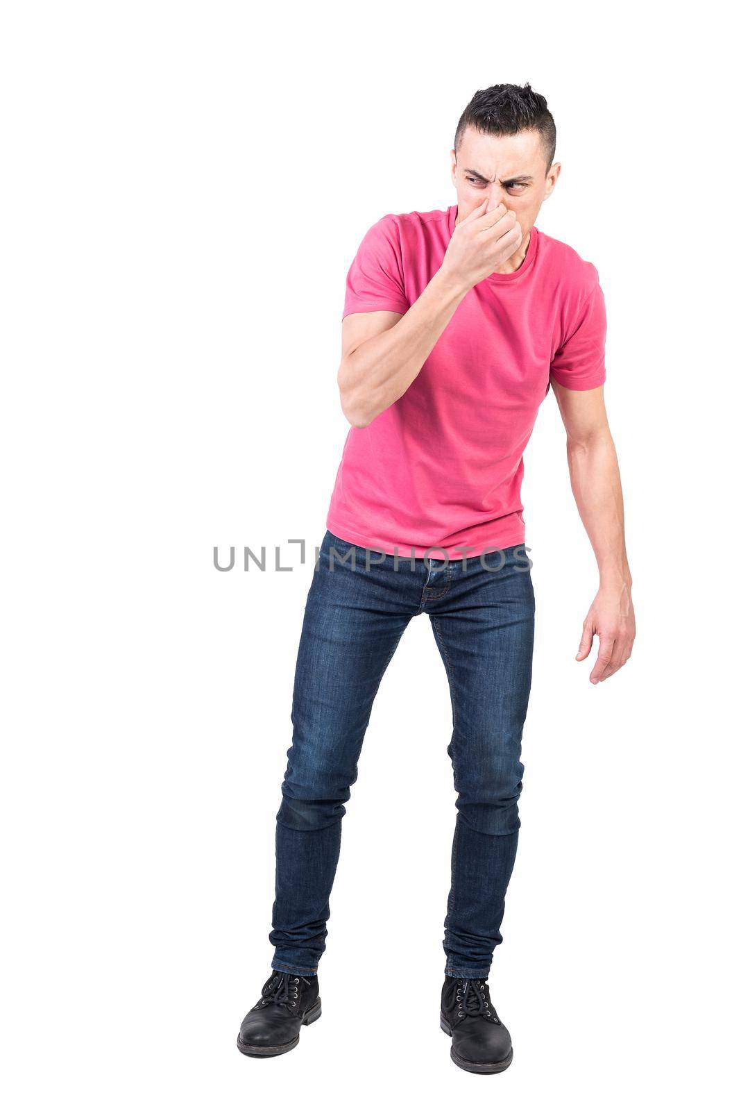 Full body of male model covering nose from bad smell while standing in studio against white background