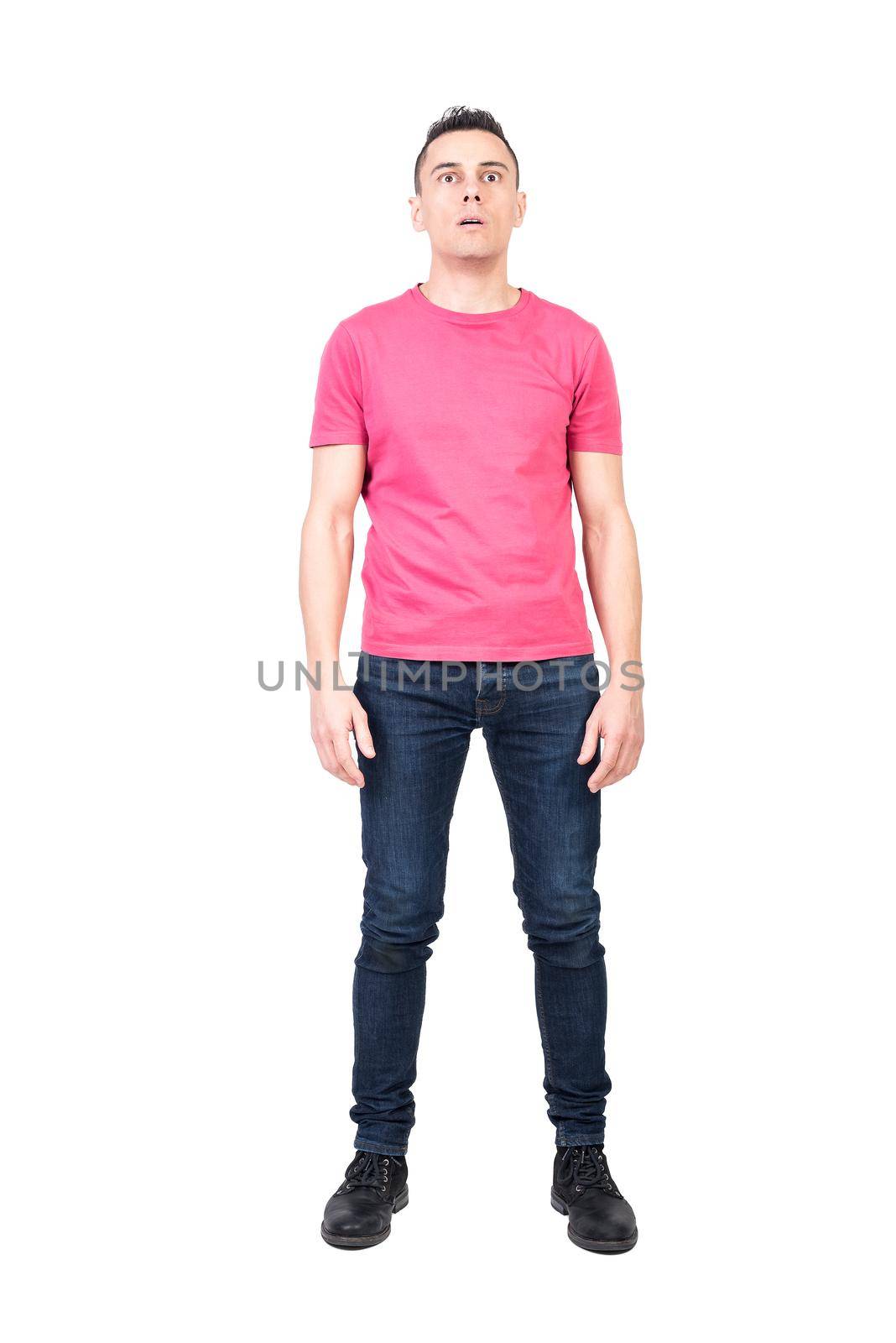 Full length astonished male in jeans and pink t shirt opening mouth and looking at camera in shock isolated on white background