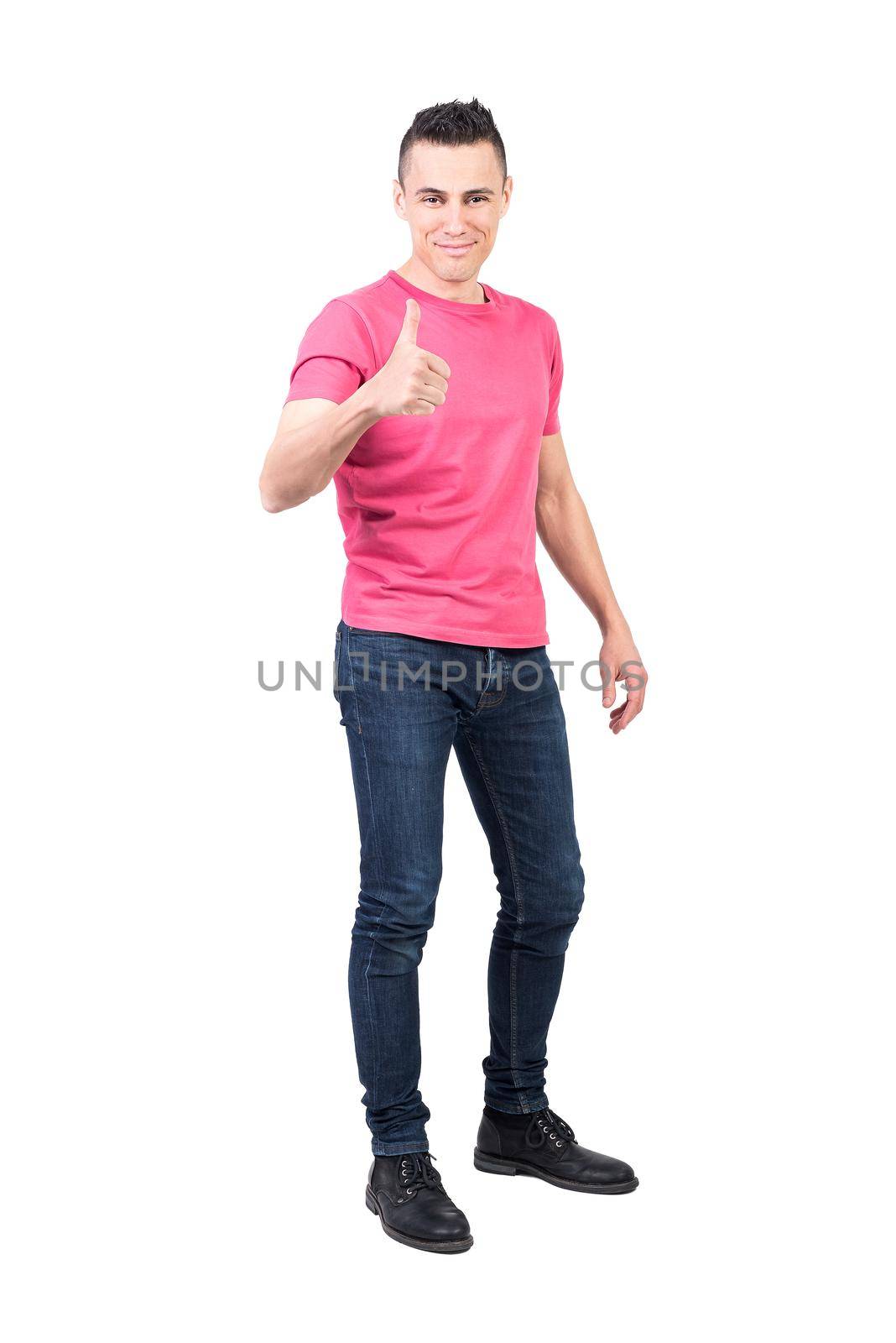 Full body of confident positive young male model with dark hair in casual clothes smiling and looking at camera while showing thumb up gesture isolated on white background