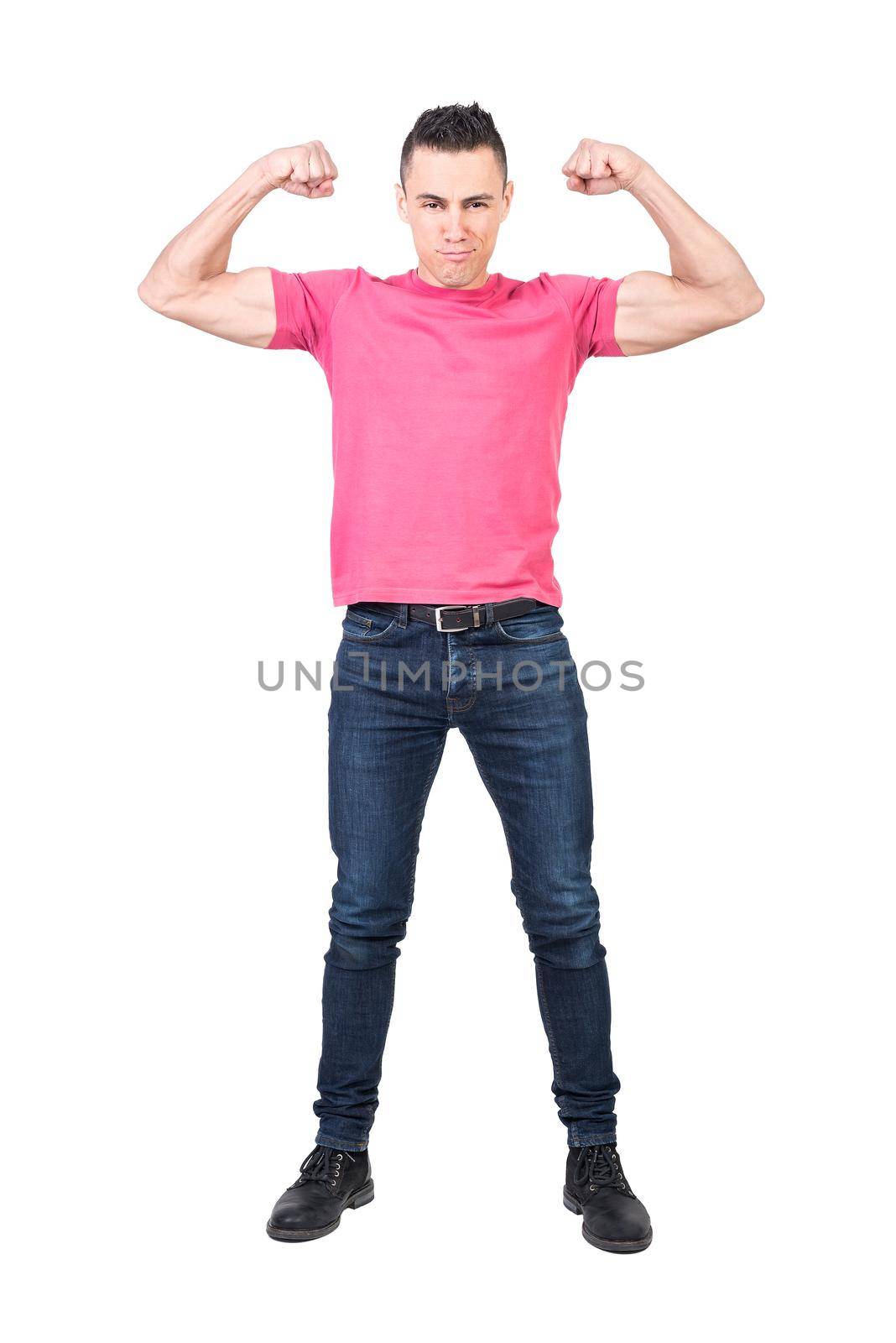 Full body of young self assured muscular male model in pink t shirt and jeans showing biceps and looking at camera isolated on white background