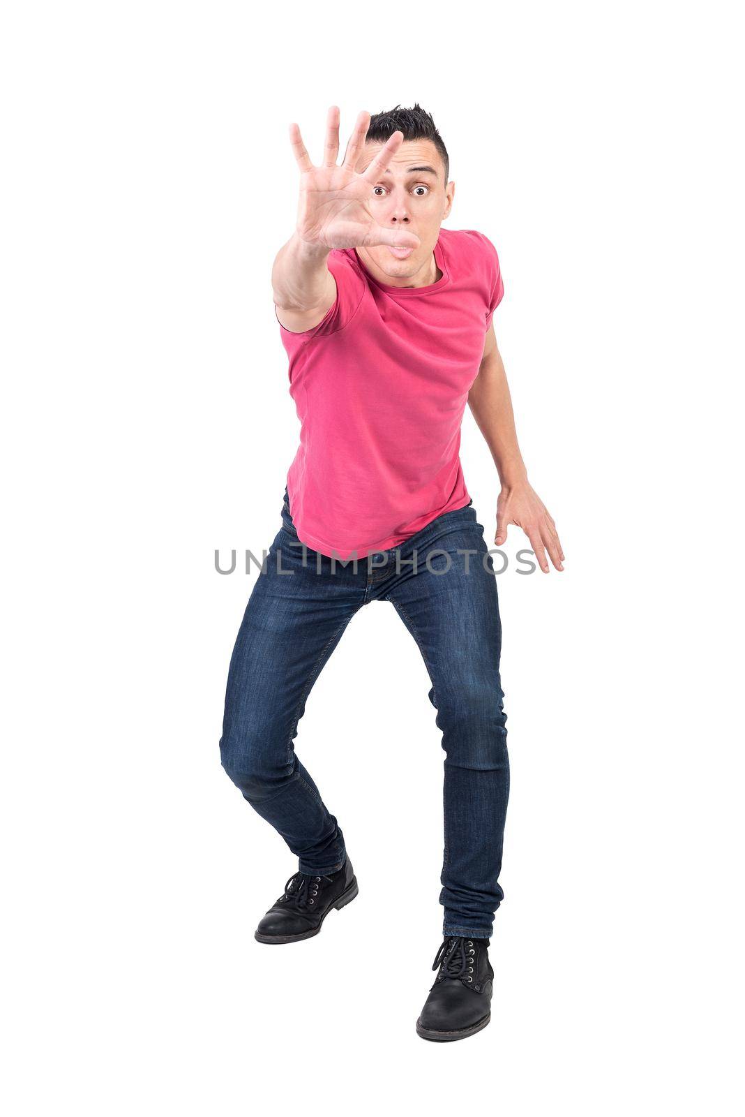 Full body of surprised male with eyes wide open reaching hand to camera and showing rejection on white background