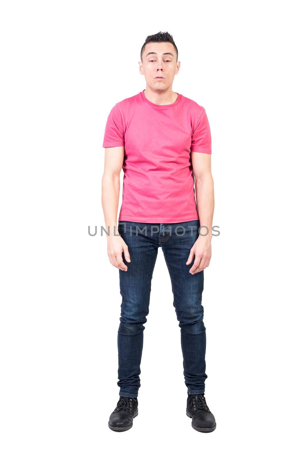 Full body of exhausted sleepy male model in casual clothes woken up early in morning in studio against white background