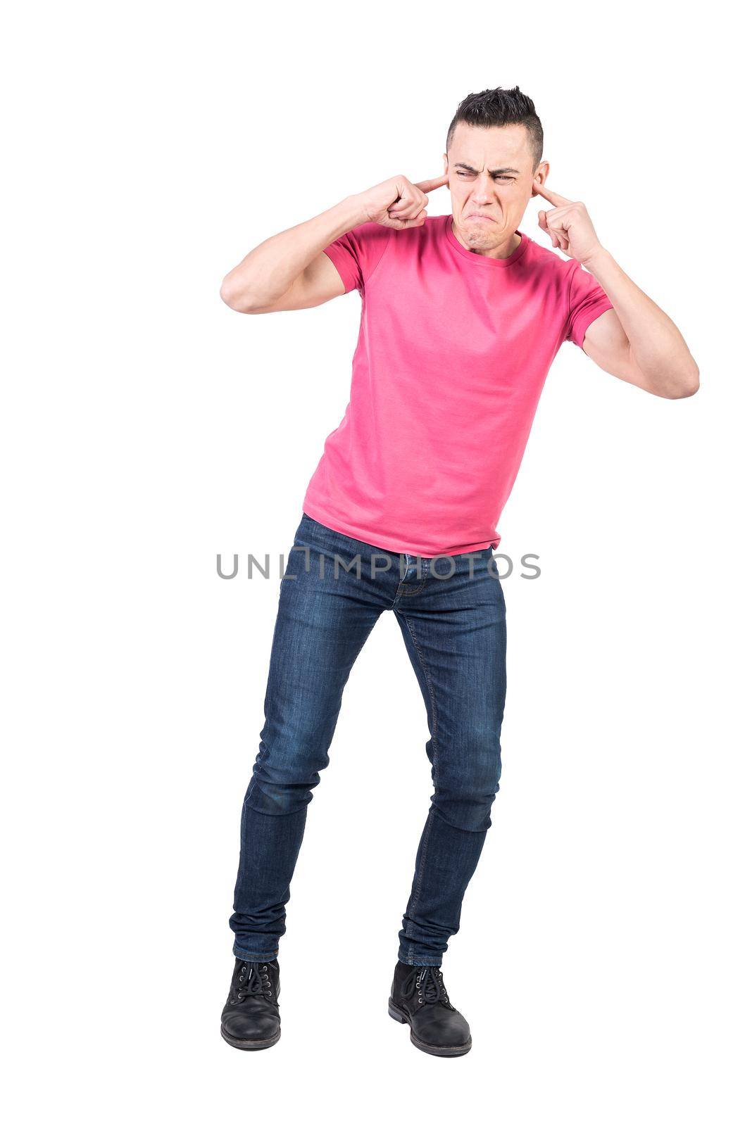Full body of annoyed male model covering ears from disgusting noise and making disgruntled face against white background