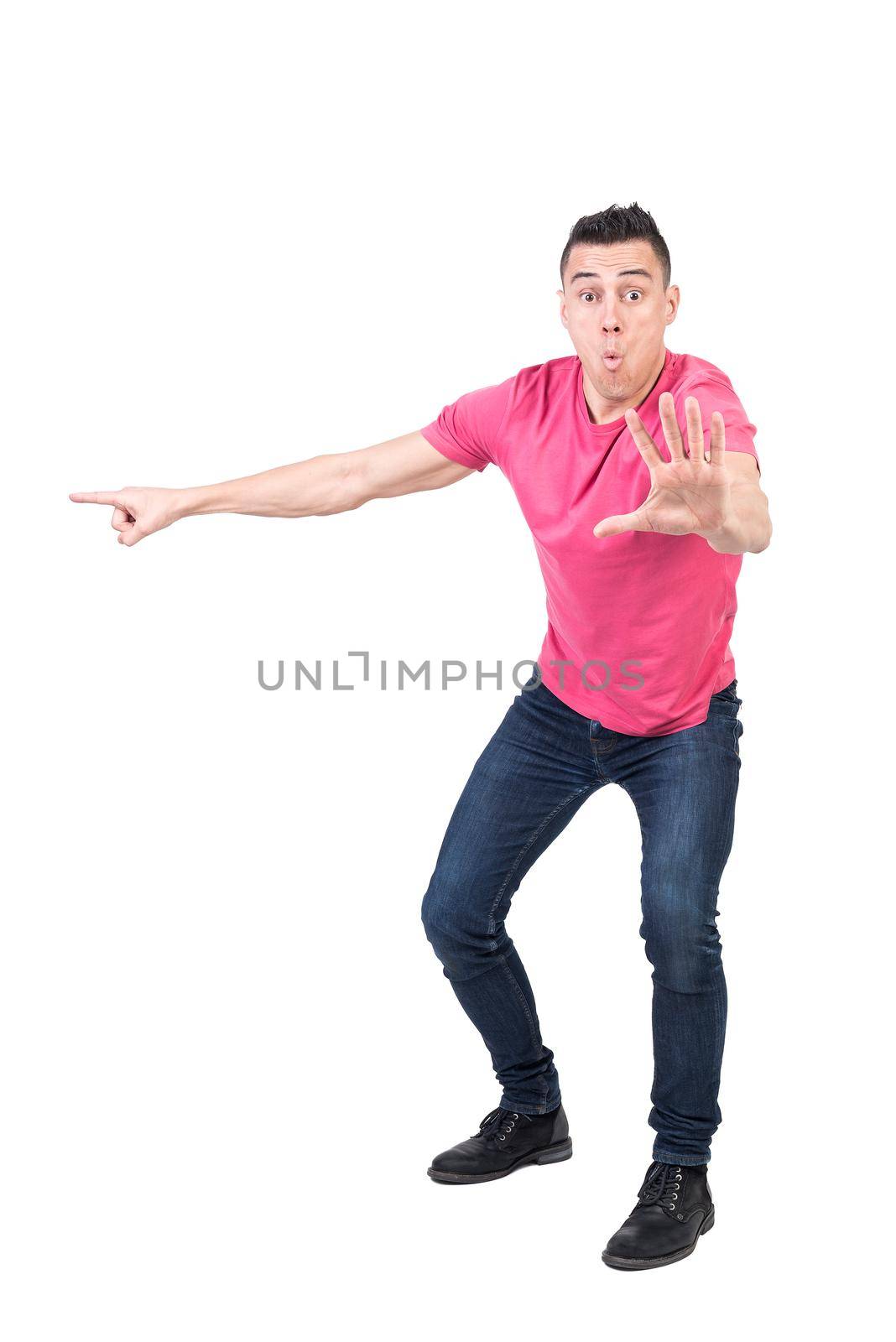 Full body of shocked male model pointing aside and showing stop gesture while looking at camera isolated on white background
