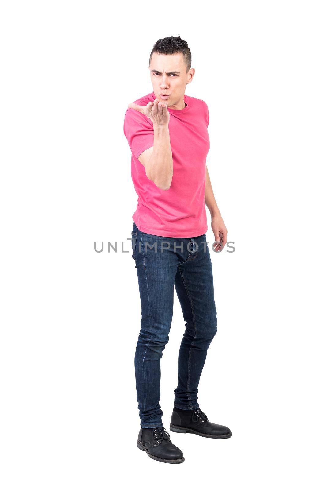 Full body of romantic male in casual clothes sending air kiss to camera while looking at camera against white background