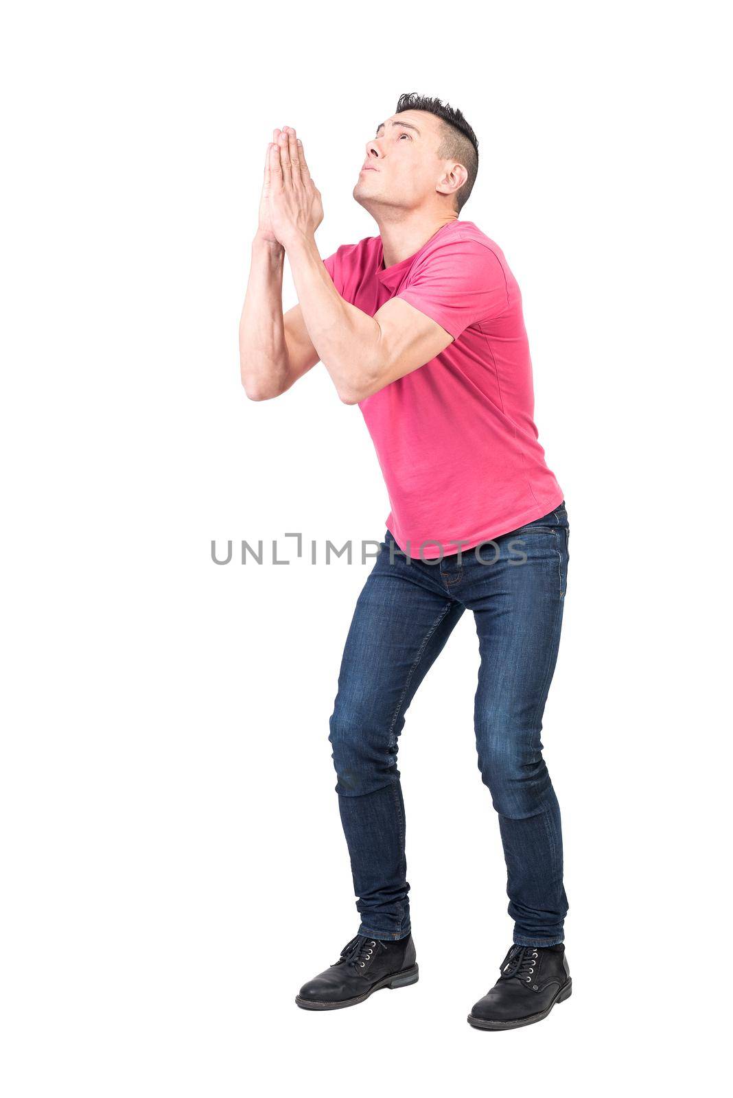 Full body of male with imploring expression begging with praying hands and hoping for help on white background
