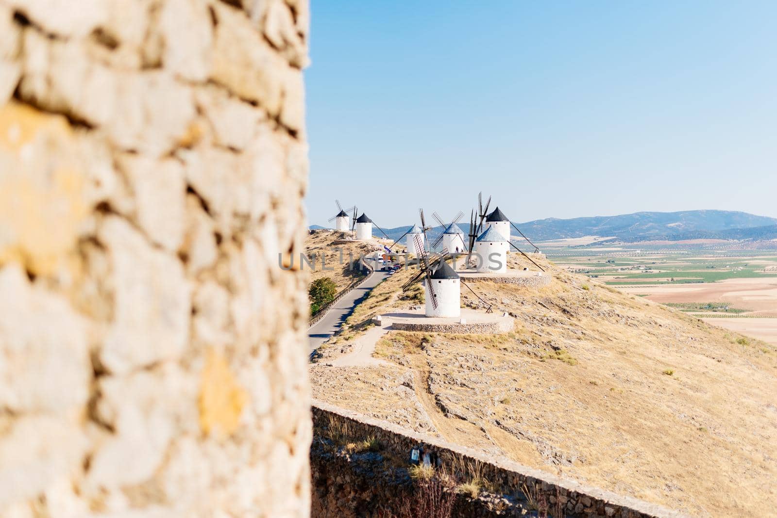 Selective focus on a group of historic windmills on a hillside with fields in the background the image