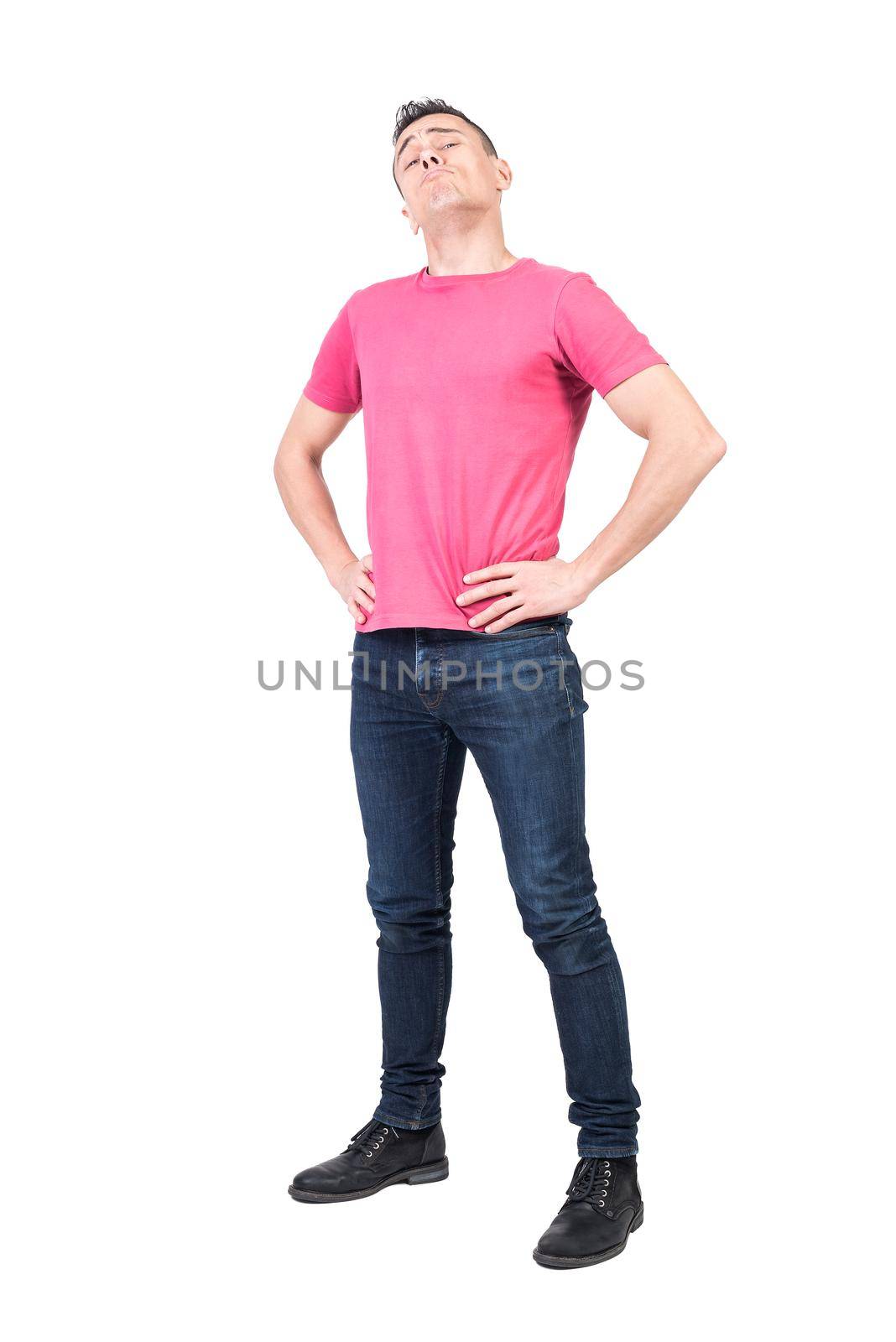 Full body of self assured haughty male model standing with hands on waist on white background