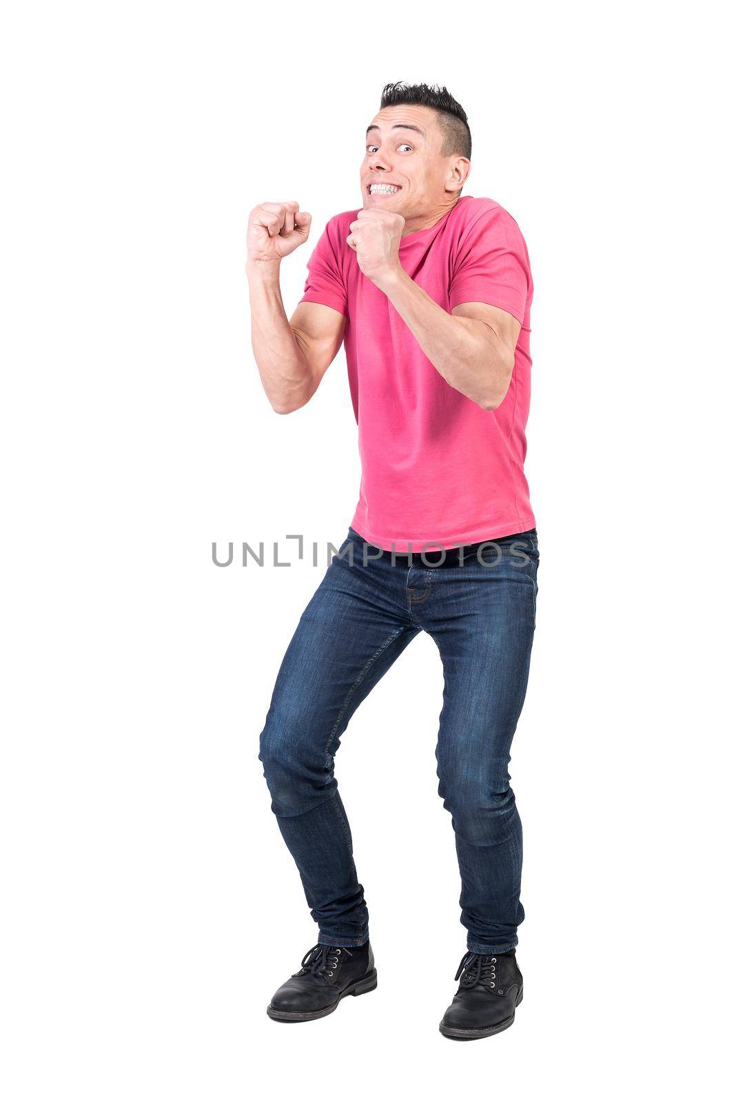 Full body of content male model with clenched fists looking at camera isolated on white background in modern light studio