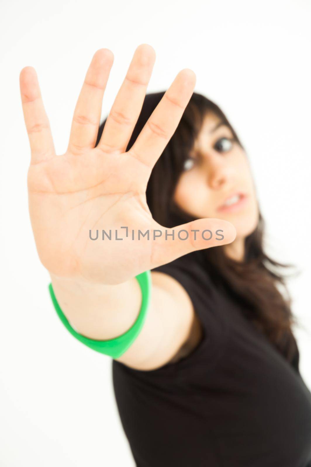 Modern pretty brunette girl with arm and palm extended for you to stop, on white background, close up