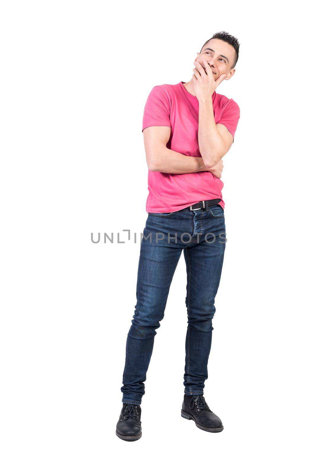 Full body of dreamy man covering mouth with hand and looking up while standing isolated on white background in light studio