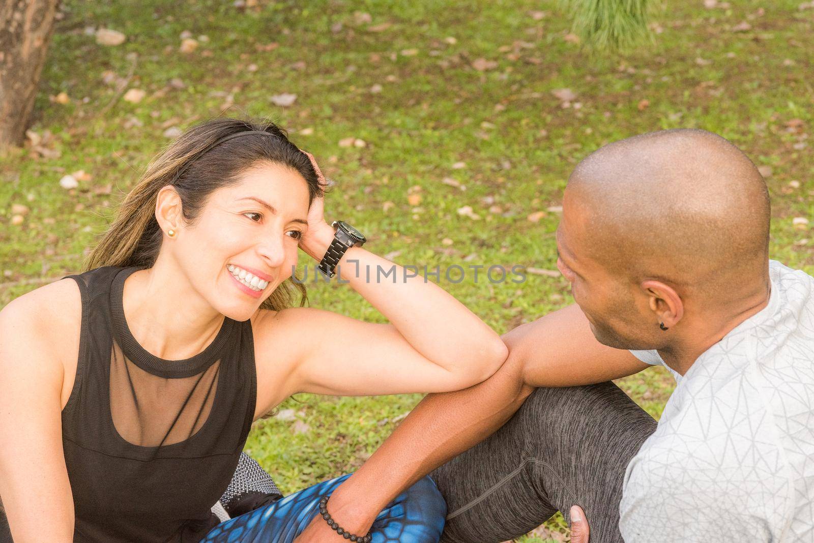 Sportswoman taking a break with her sportsboyfriend after a strenuous workout. Multi-ethnic couple exercising outdoors.
