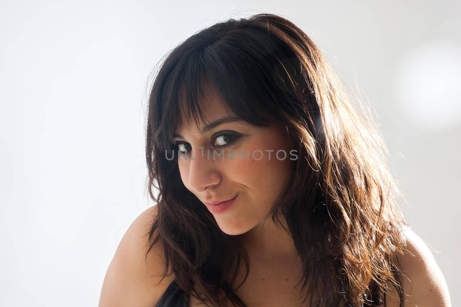 Pretty brunette girl with long hair, smiling and looking at camera on white background, close up