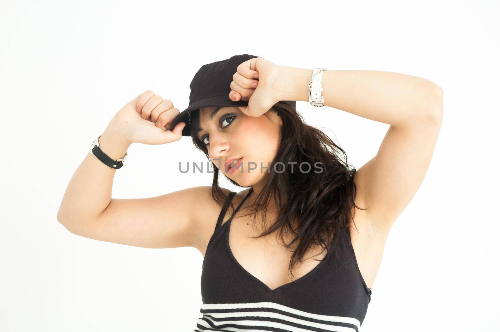 Modern pretty brunette girl putting on the cap looking at camera, on white background, mid shot