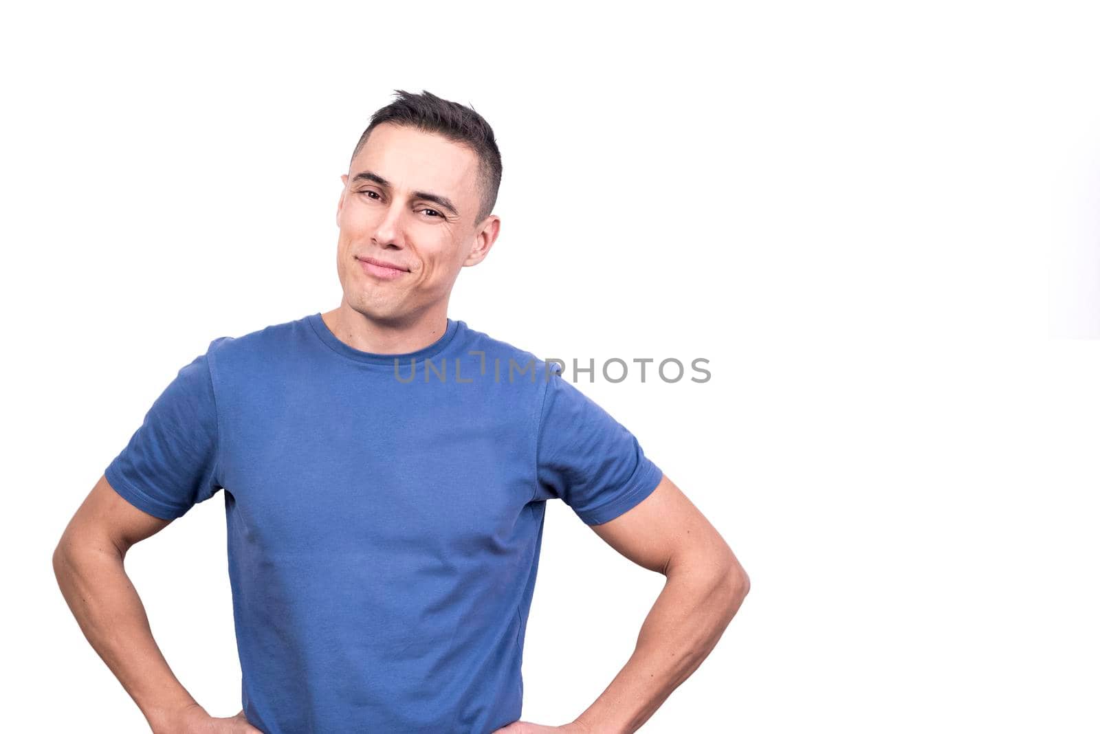 Studio portrait with white background of a man smiling relaxed with his hands on hips