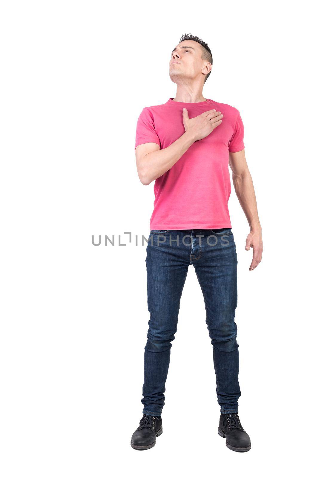 Full body of honorable male patriot looking up with hand on chest while standing isolated on white background in light studio