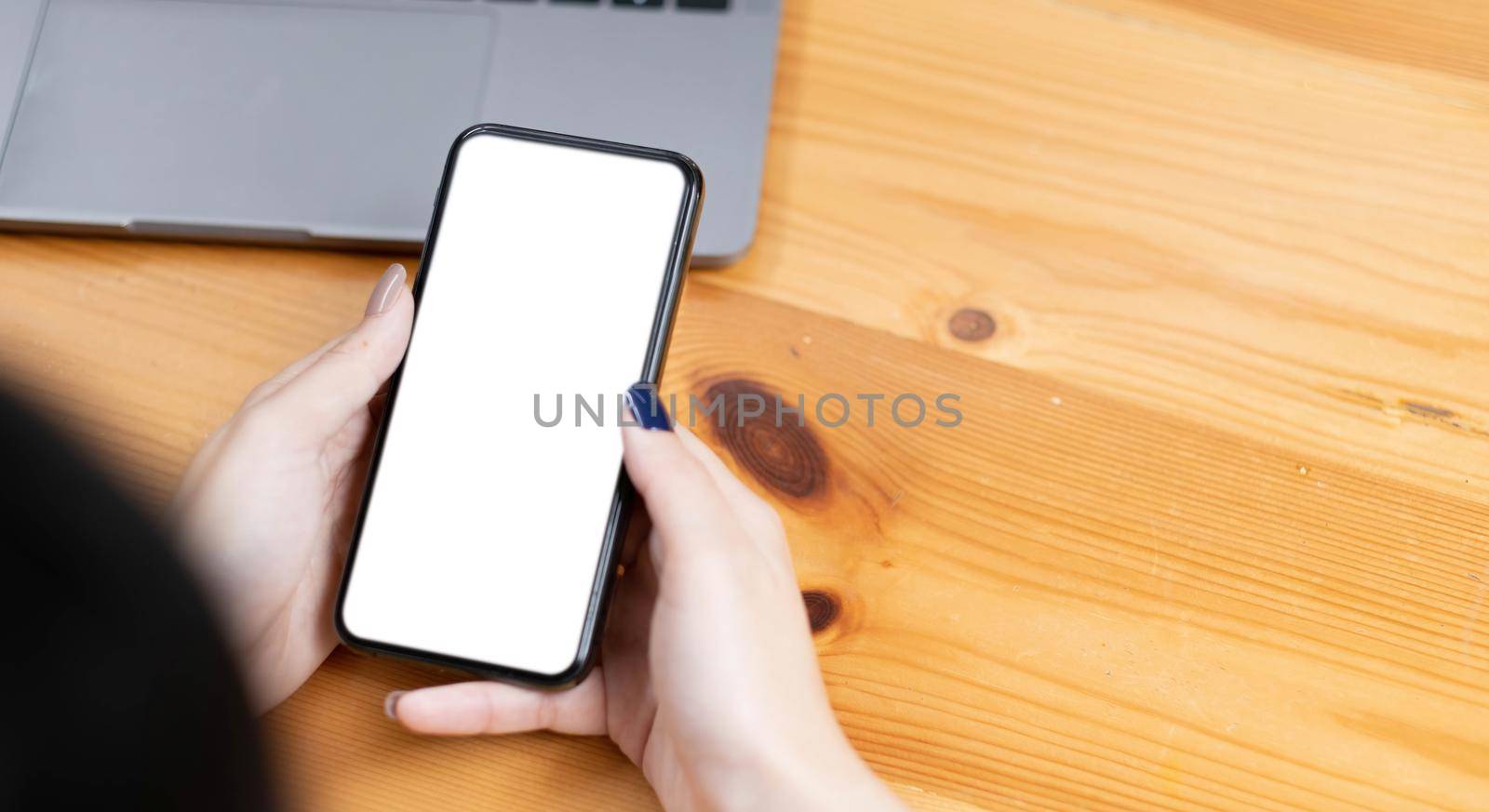 hand woman using a telephone, empty screen smart phone and computer on wooden table top view