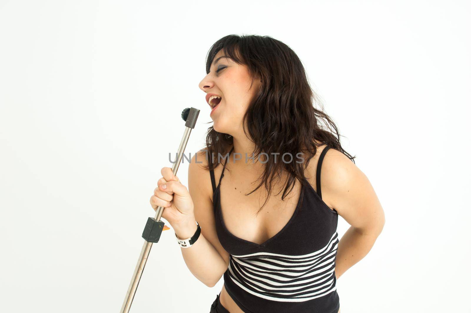 Pretty and crazy brunette girl singing with an imaginary microphone, on white background, mid shot