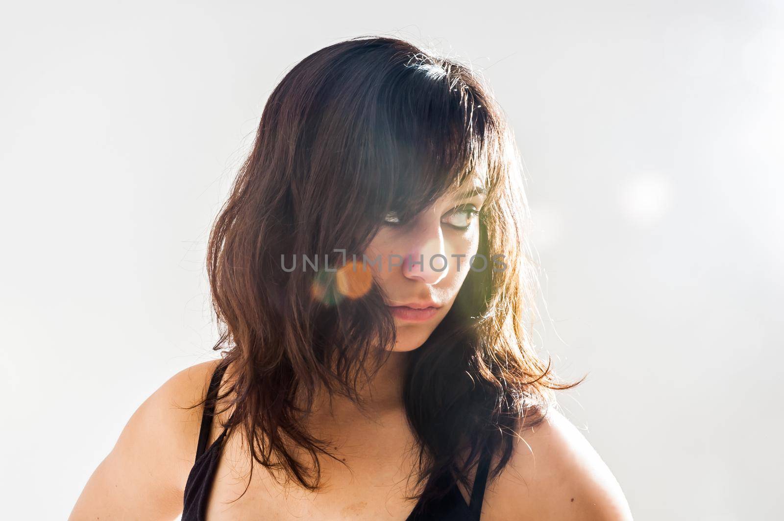 Thoughtful pretty brunette girl with long hair, looking sideways, on white background , close up