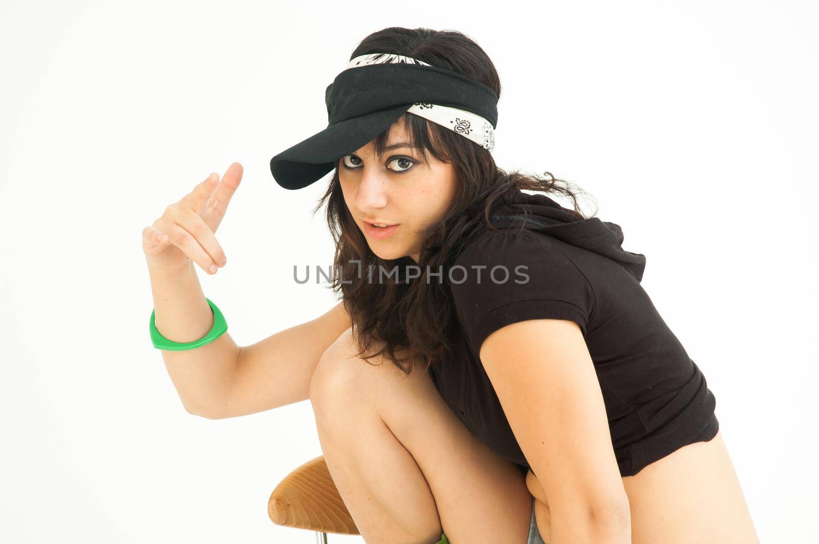 Modern pretty brunette girl rapping with shirt, short jeans and cap looking at camera, on white background, mid shot