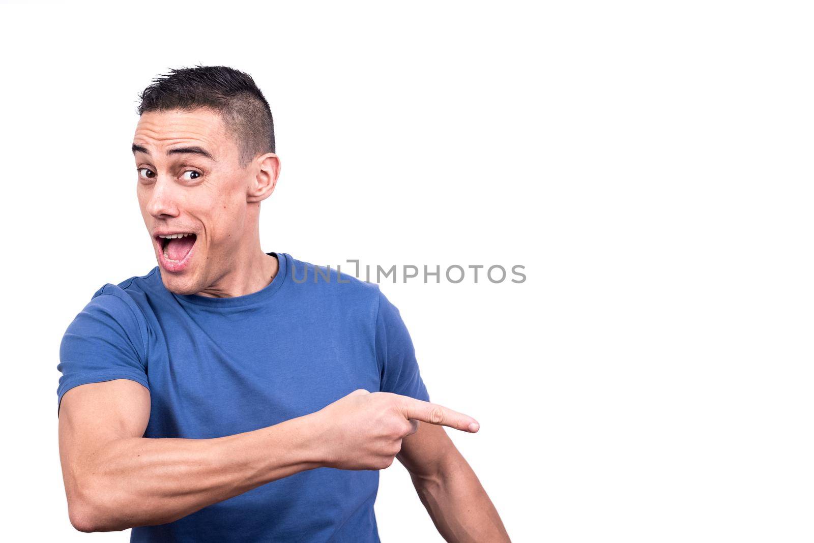 Studio portrait of a man smiling with surprise expression while pointing to the side with one finger