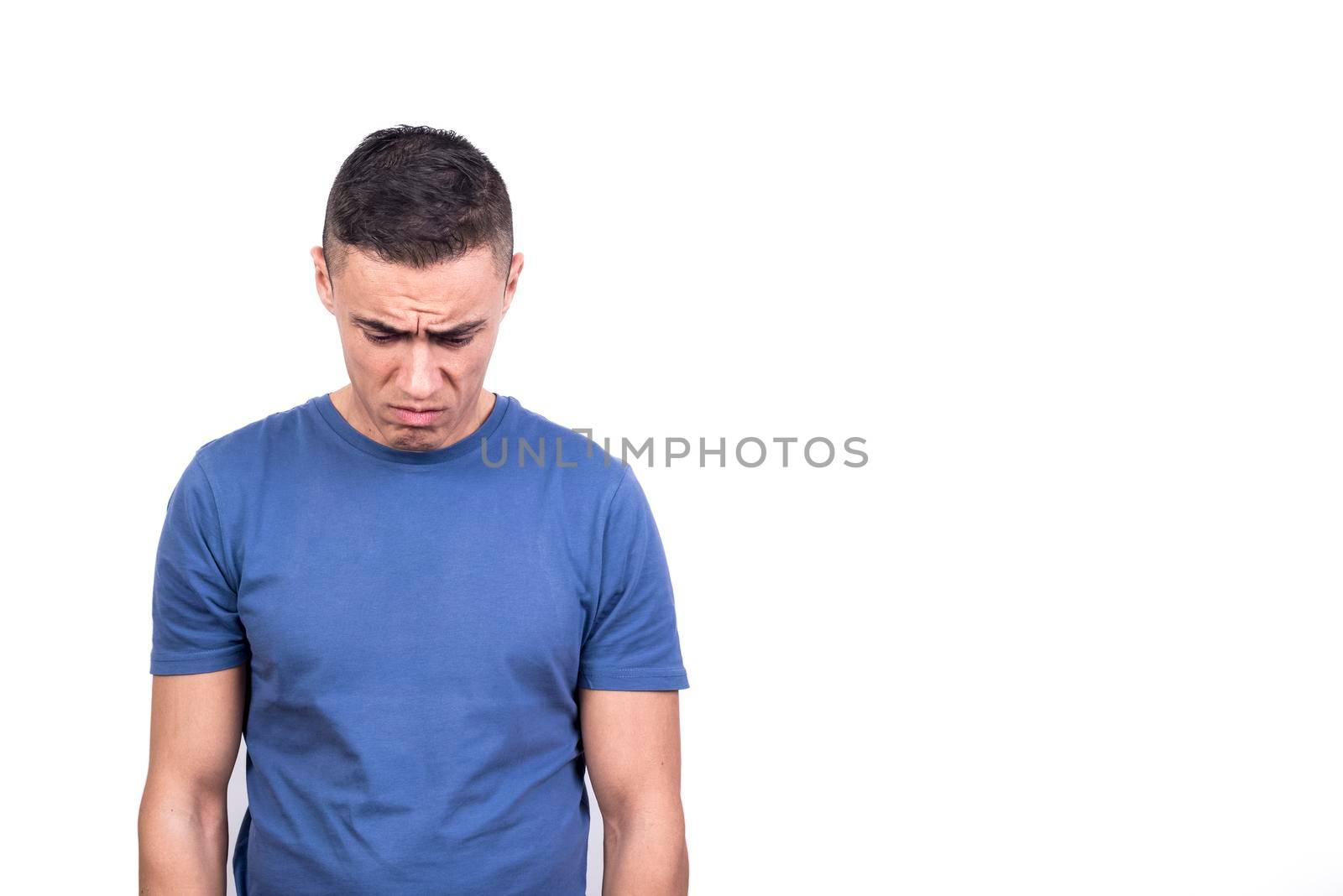 Studio portrait with white background of a man looking down with sad expression