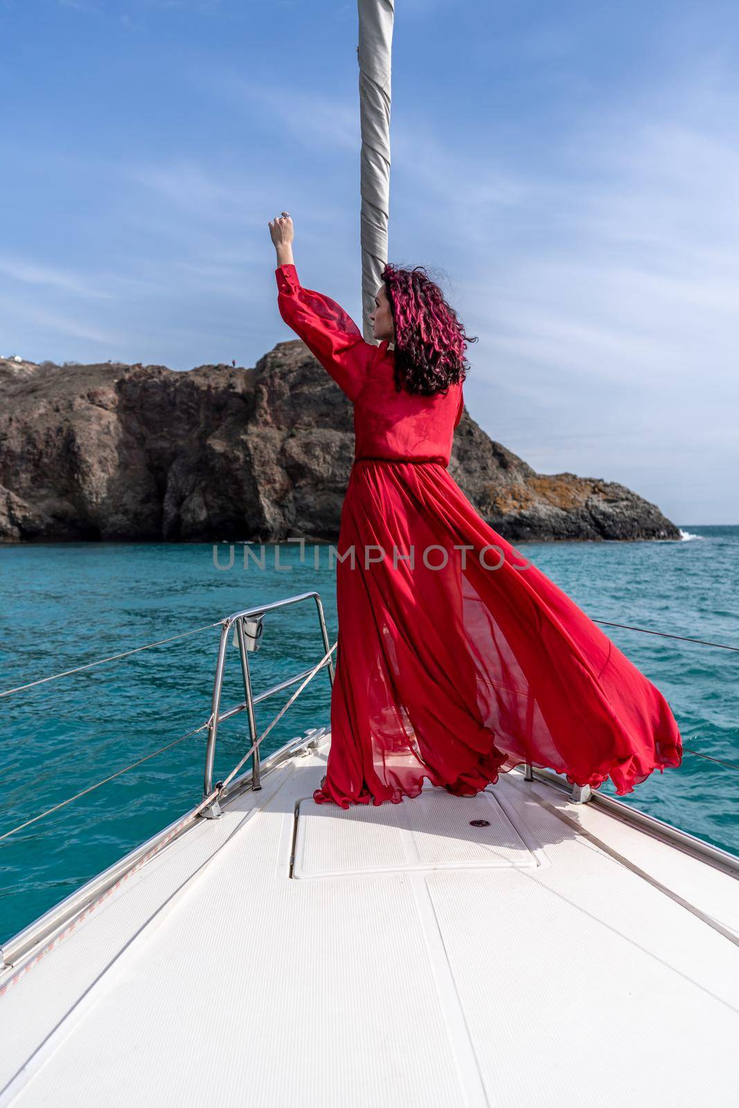 Attractive middle-aged woman in a red dress on a yacht on a summer day. Luxury summer adventure, outdoor activities