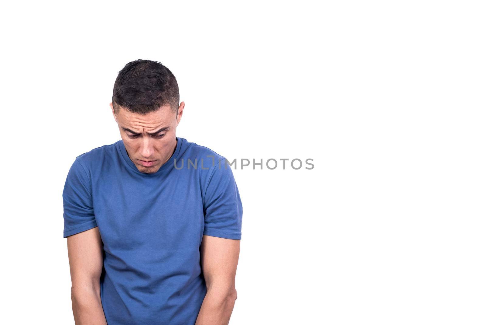 Studio portrait with white background of a man looking down at the ground with a guilty look