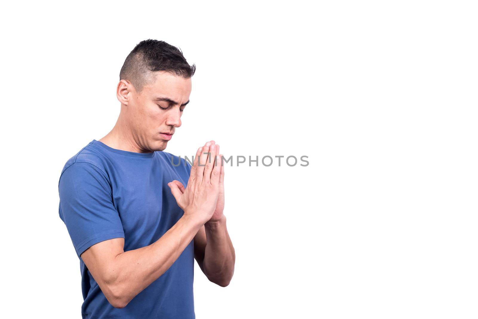 Studio portrait of a man with hands together as praying concentrated in a white background