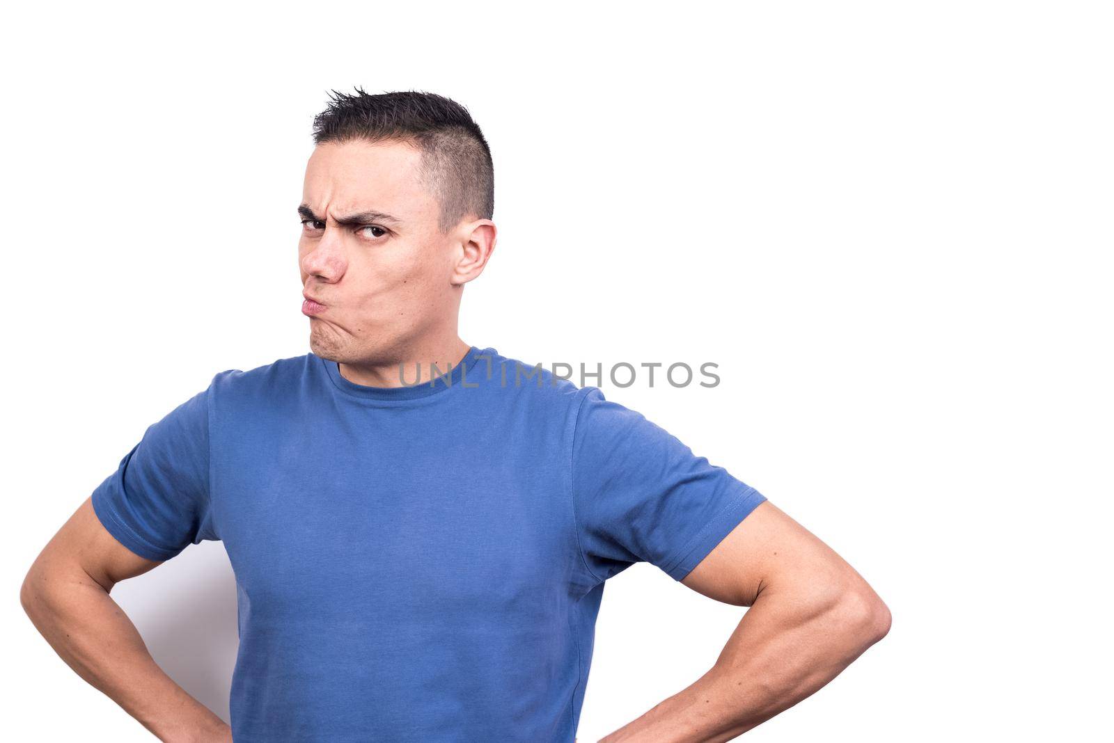 Studio portrait with white background of a man with his hands on his hips and a doubtful expression