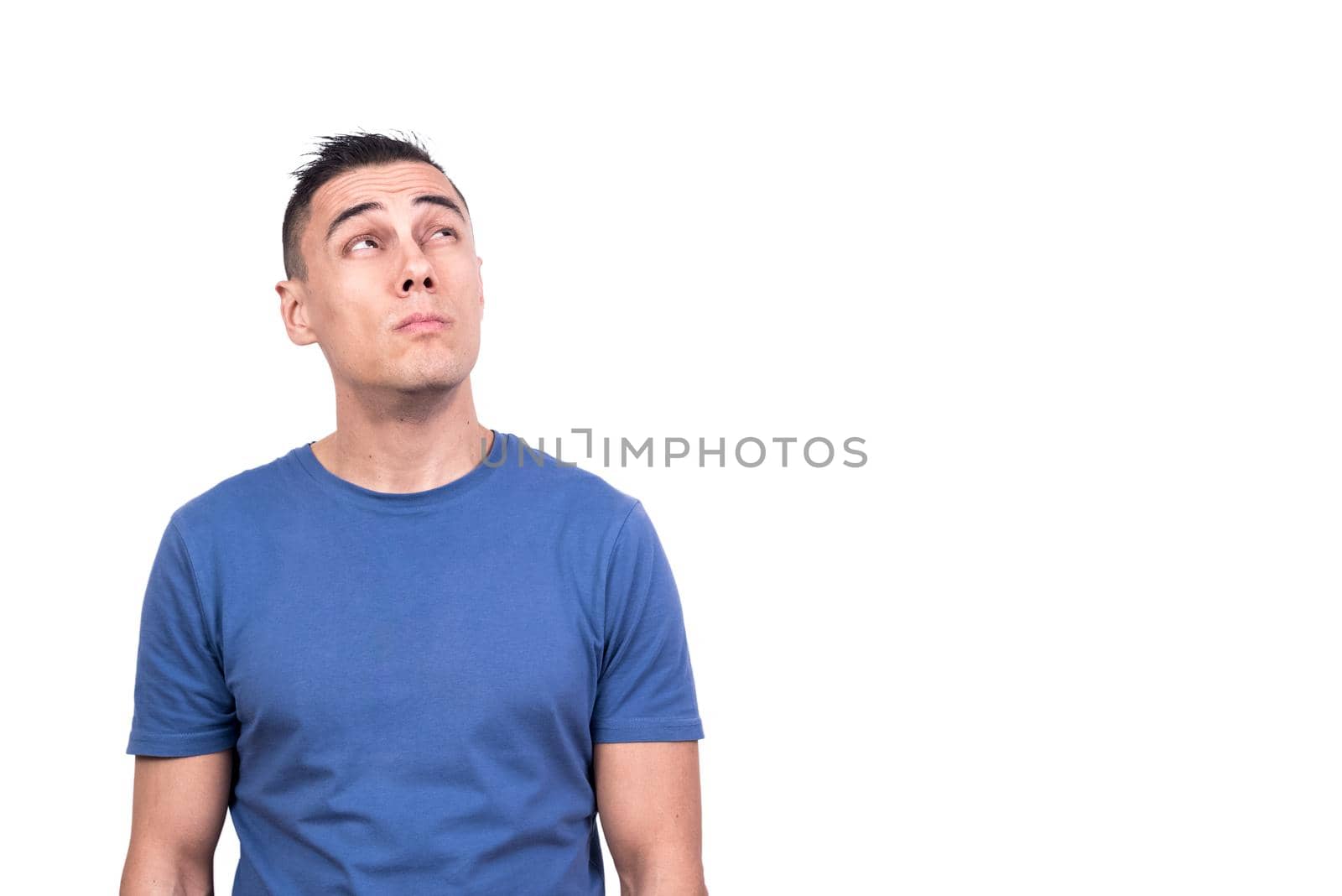 Studio photo with white background of a man standing looking up with distrustful expression