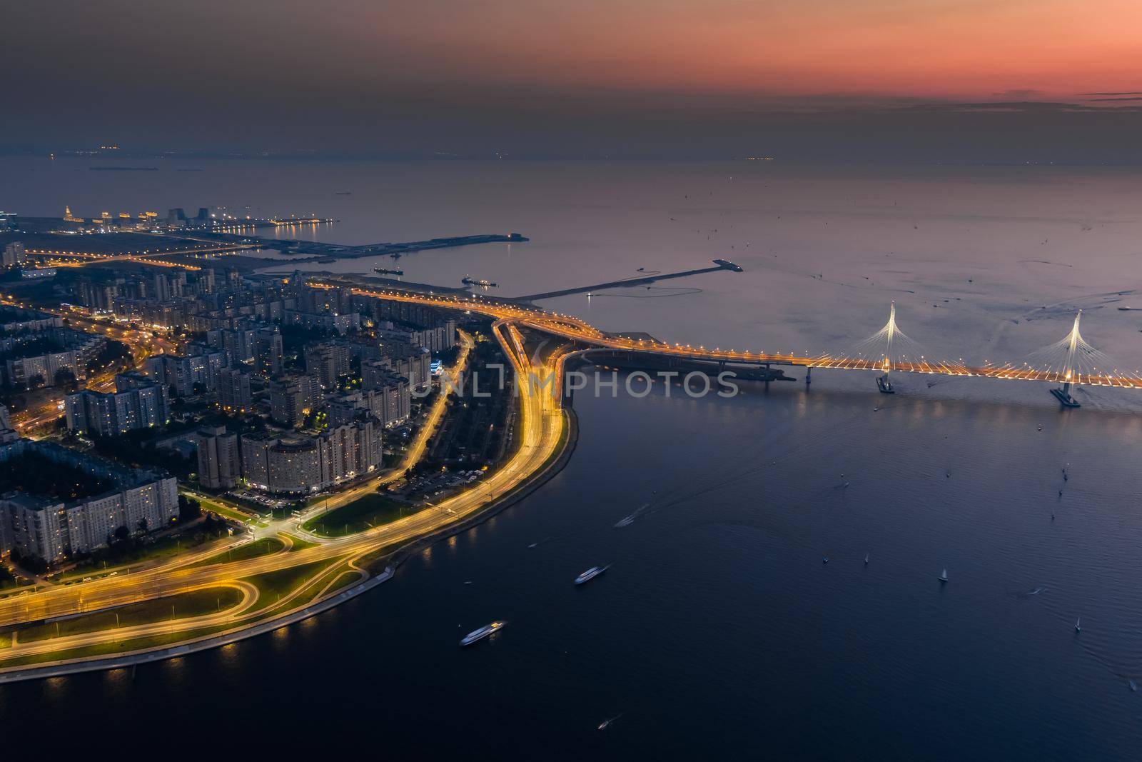 A picturesque sunset over the cable-stayed bridge and Vasilevsky island, passenger sea port, illuminated highway. High quality photo