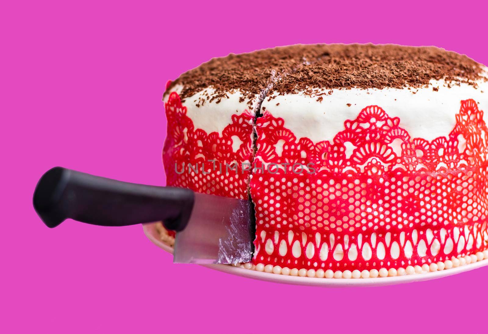 homemade cake with cream and red lace decorated with chocolate chips. The knife is ready to cut the cake. Flour dessert. Sweet cake ready to eat. pink background. High quality photo