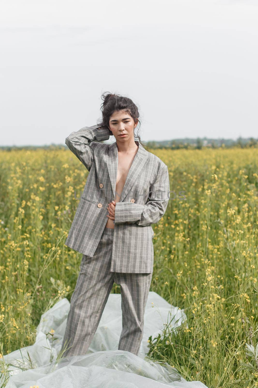 An Asian model poses in a field of yellow flowers for a clothing brand, polyethylene is the main props for a photo shoot. by Annu1tochka