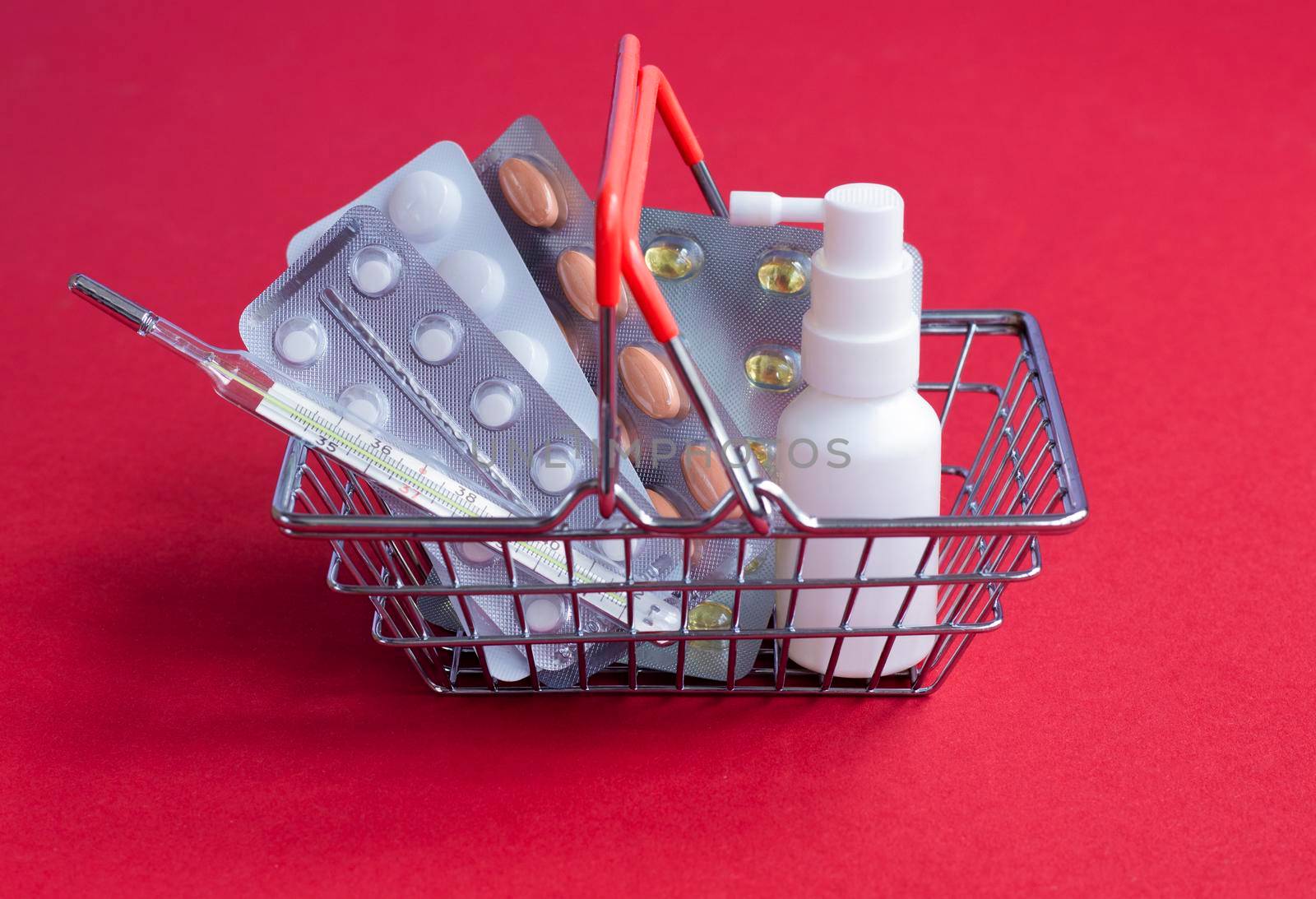 Sale and discount. Biggest medicines store. Shopping basket with tablets pills close up. Medical supplies. Essential medicines for home treatment. Medicines red background copy space red back