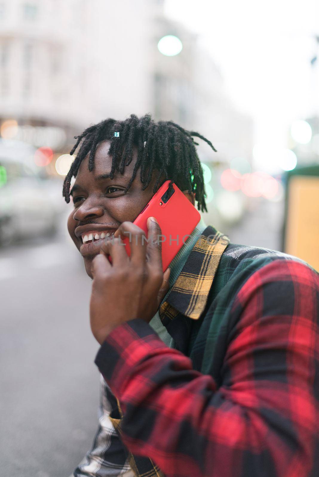 Smiling black guy talking on mobile in the city. Selective focus.