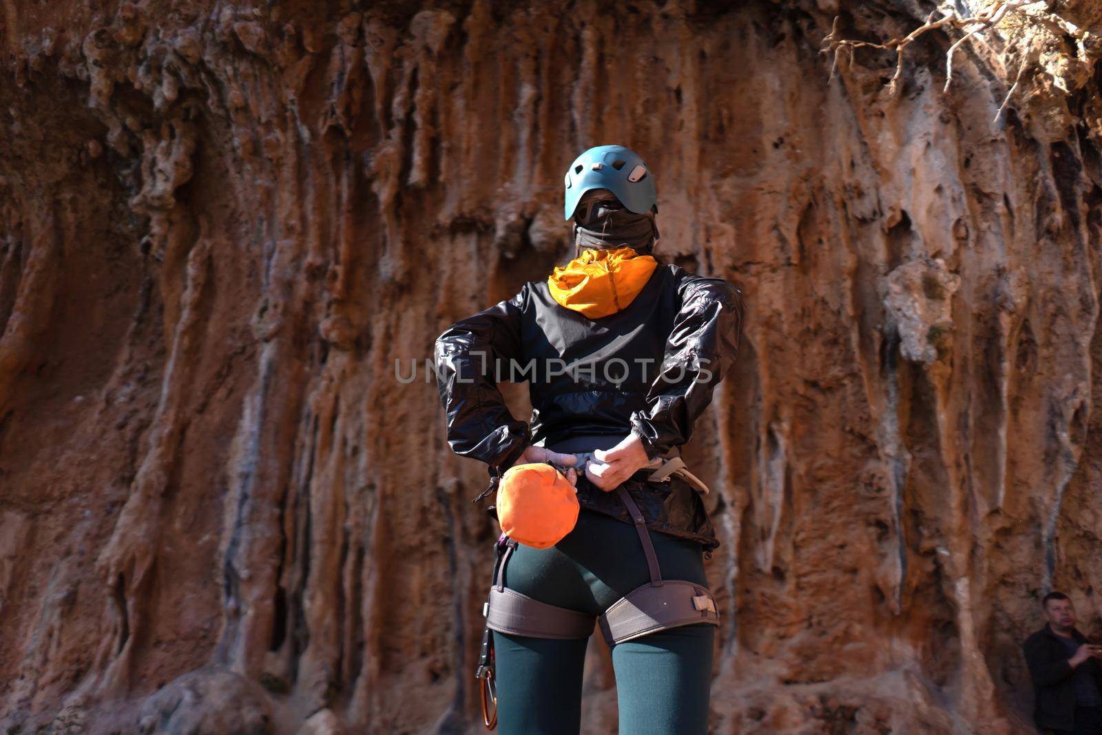 A young girl is engaged in active sports, rock climbing and mountaineering. A woman looks at a beautiful red rock and takes magnesia in her hand, getting ready for training and climbing.