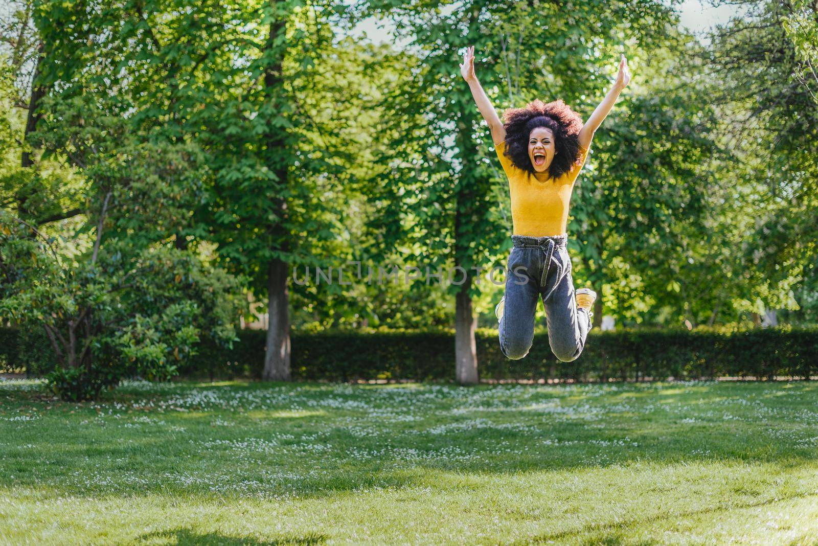 Pretty woman jumping happily in a garden. Front plane. Full body.