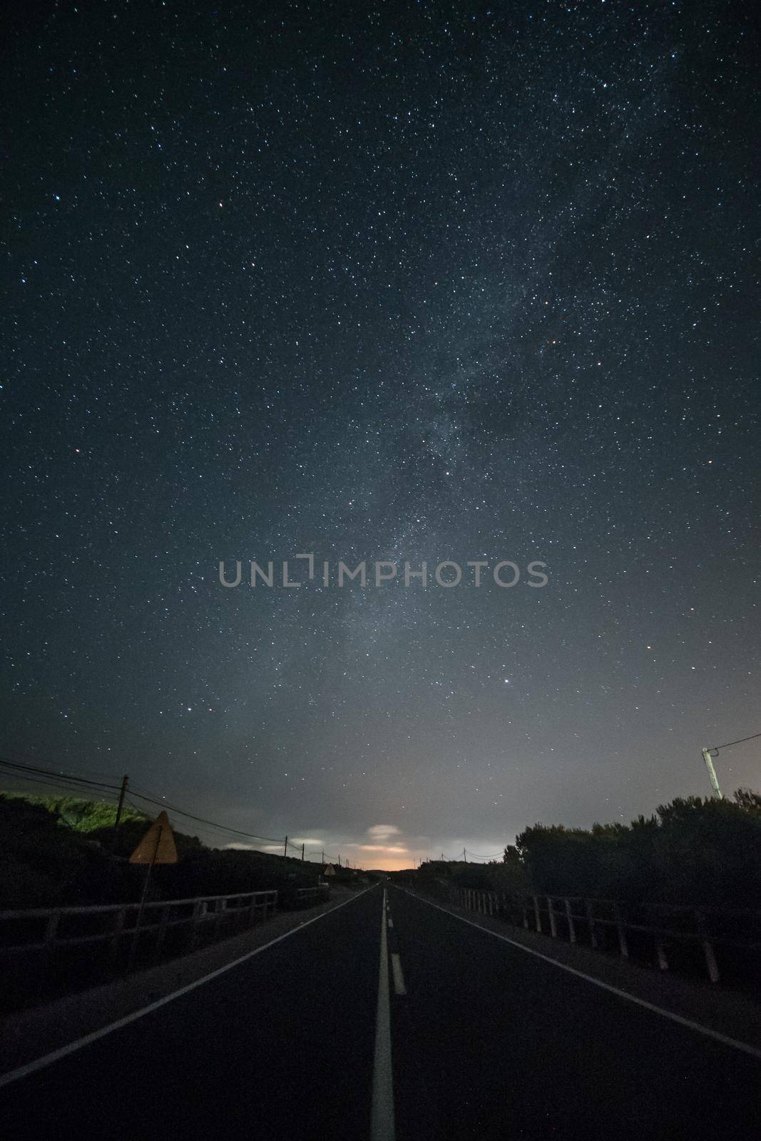 Night landscape with deserted road and starry sky. Vertical framing. Formentera island, Spain.