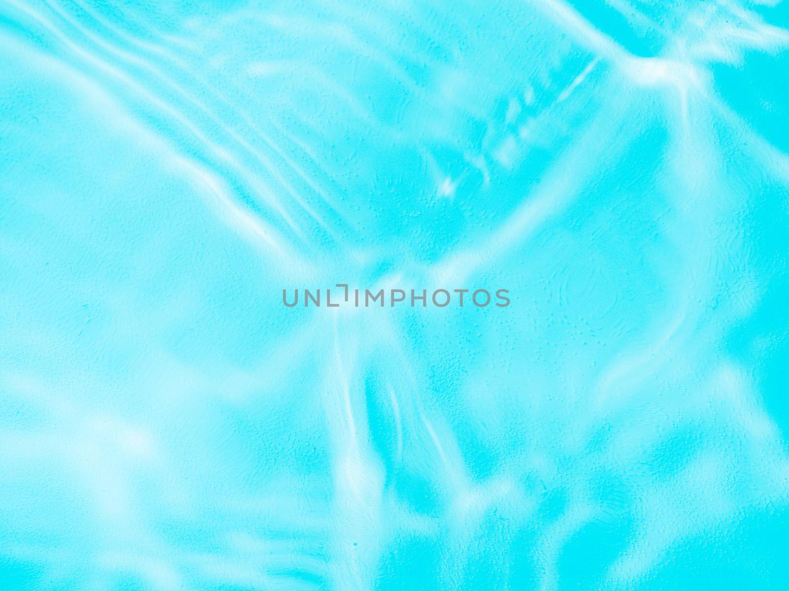 Ripple water texture on blue pool background. Shadow of water on sunlight. Mockup for product, spa or travel background. Marble blue water surface as wallpaper background